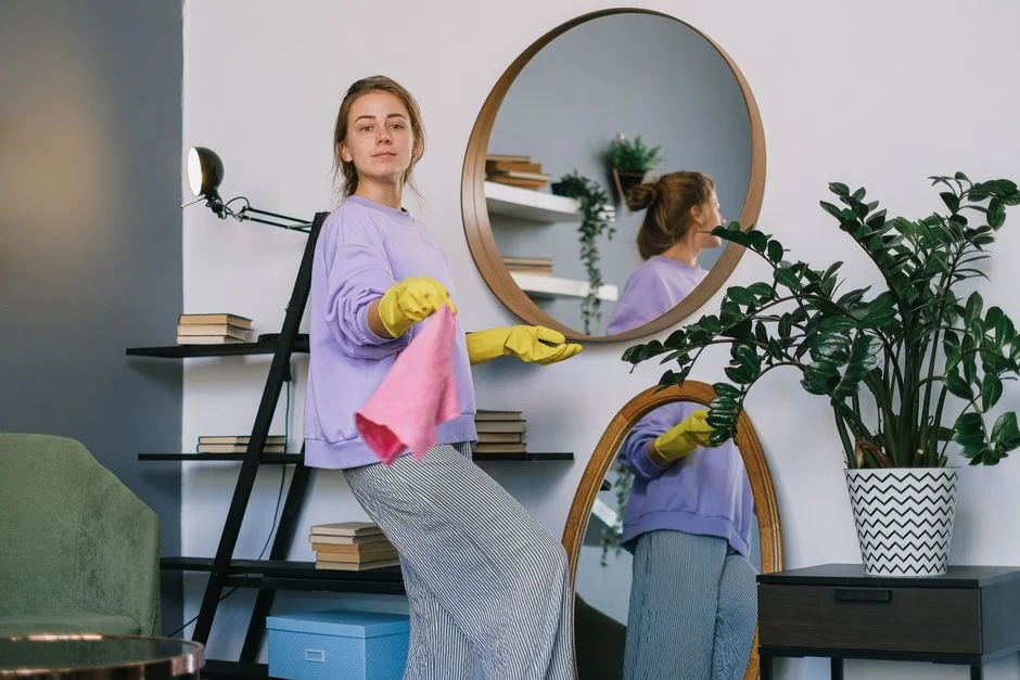 Two women in red overalls vacuuming and sweeping a modern living room.